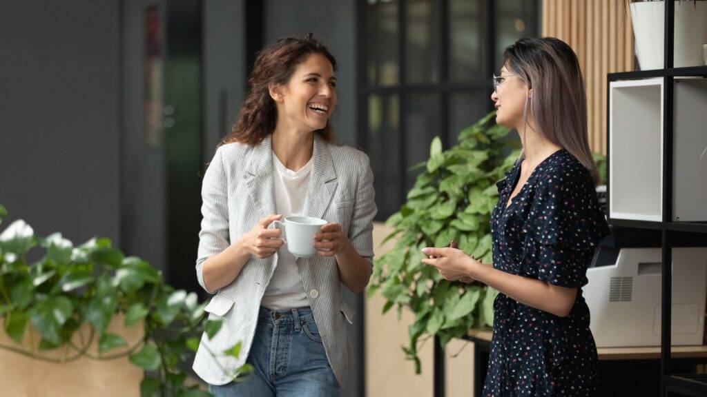 Two female coworkers chatting and laughing